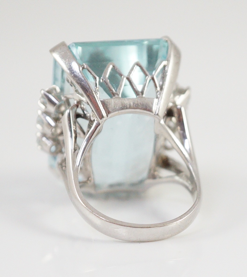 A large modern 14k white gold and emerald cut aquamarine set dress ring, flanked by six round cut diamonds